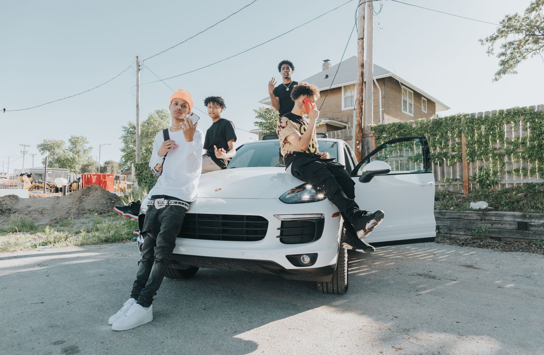 Group of young men posing on and around a car in an urban neighborhood street, Omaha, NE.
