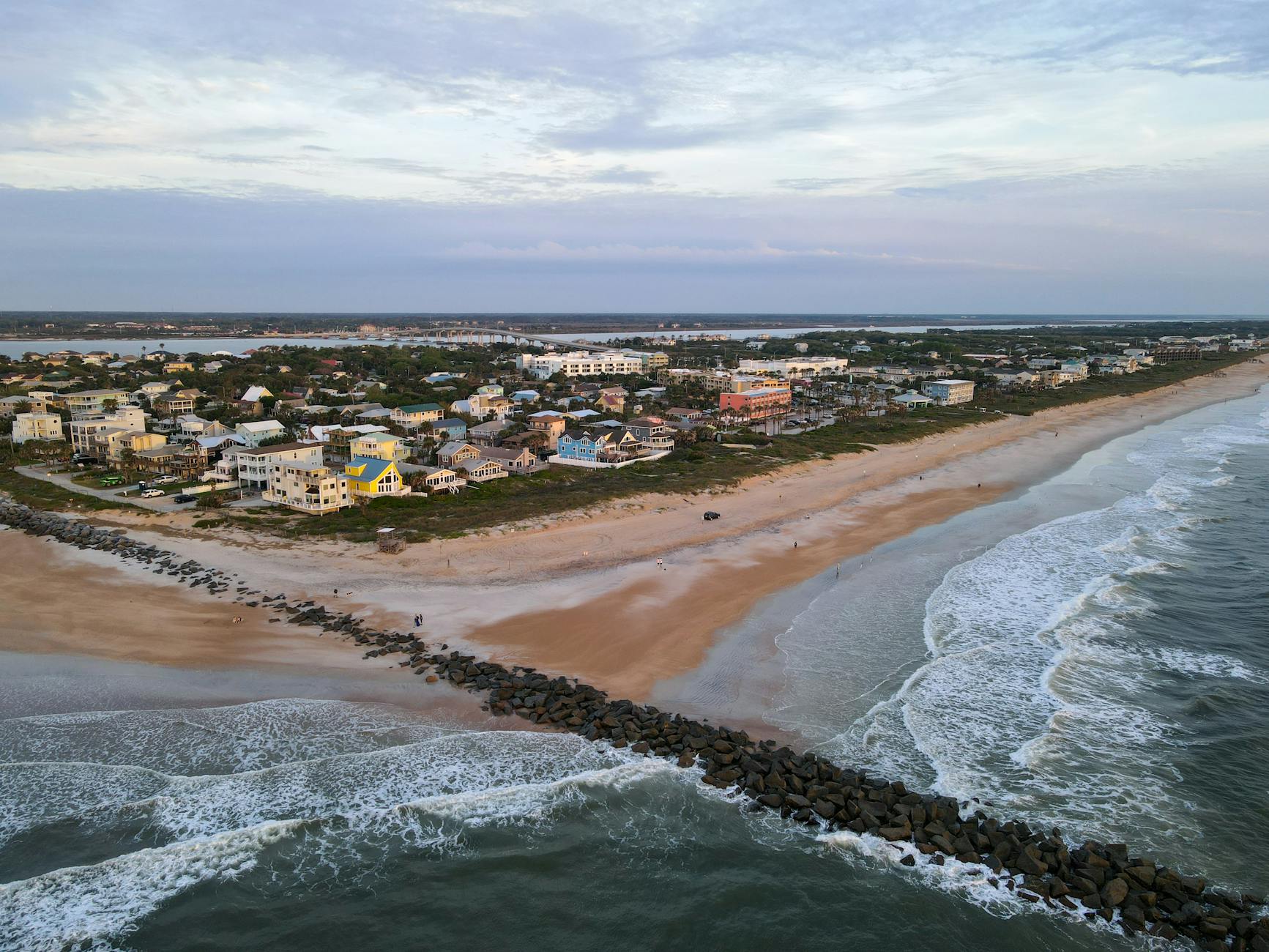 Scenic aerial photo of St. Augustine Beach, showcasing waves, sand, and coastal homes.