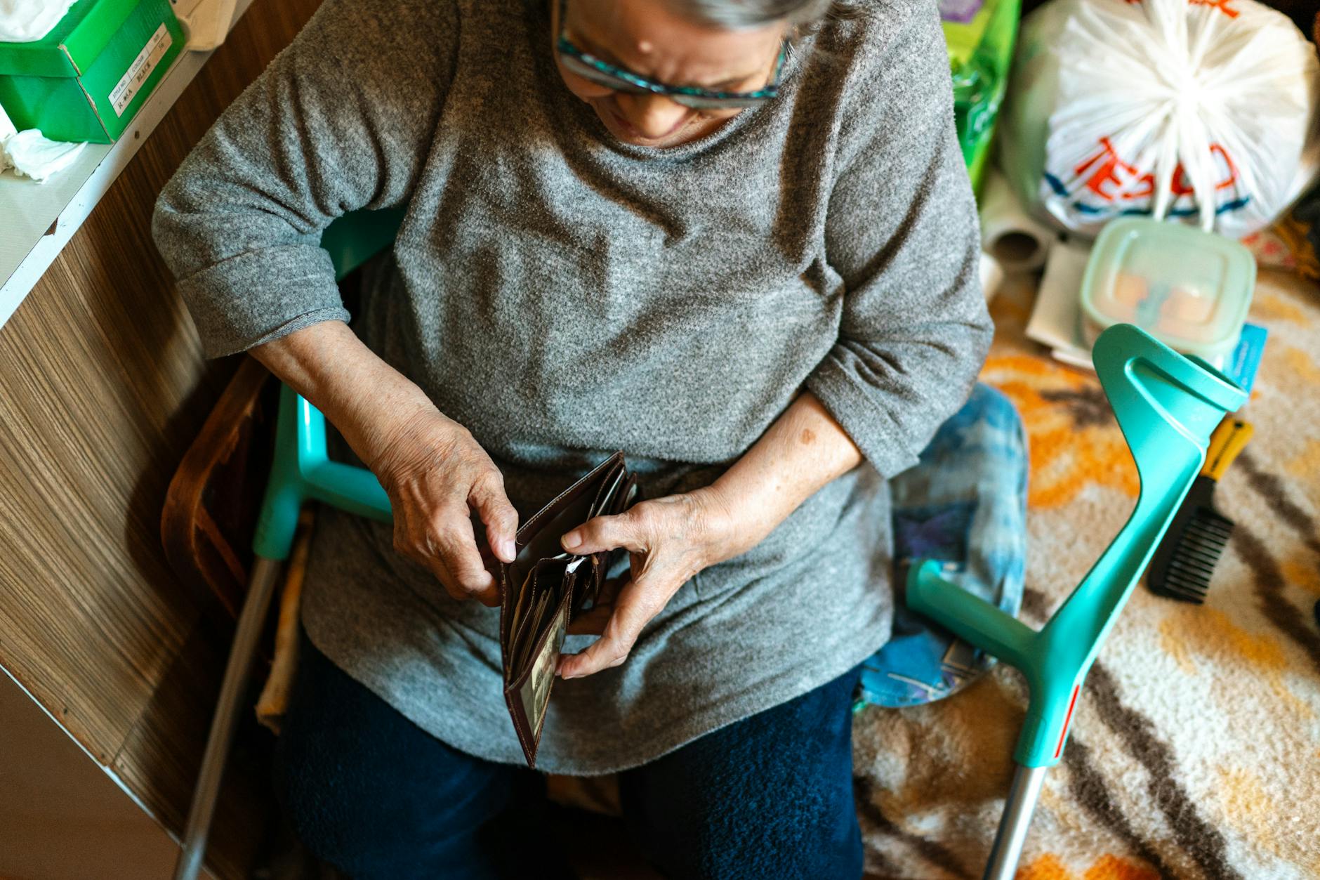 Elderly woman sitting indoors managing her wallet. Home care theme.