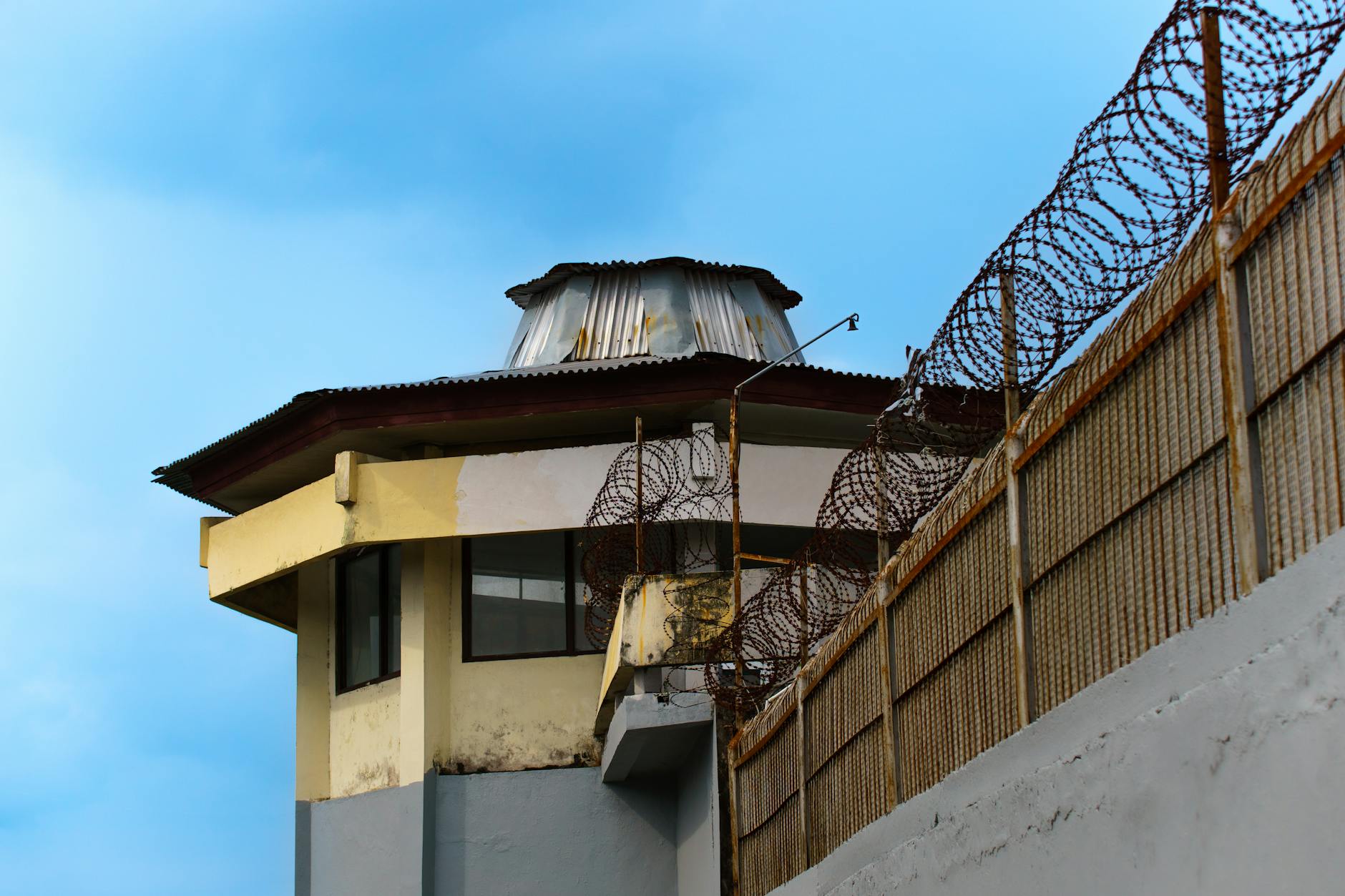 A prison watchtower with barbed wire against a clear blue sky in Bali, Indonesia.