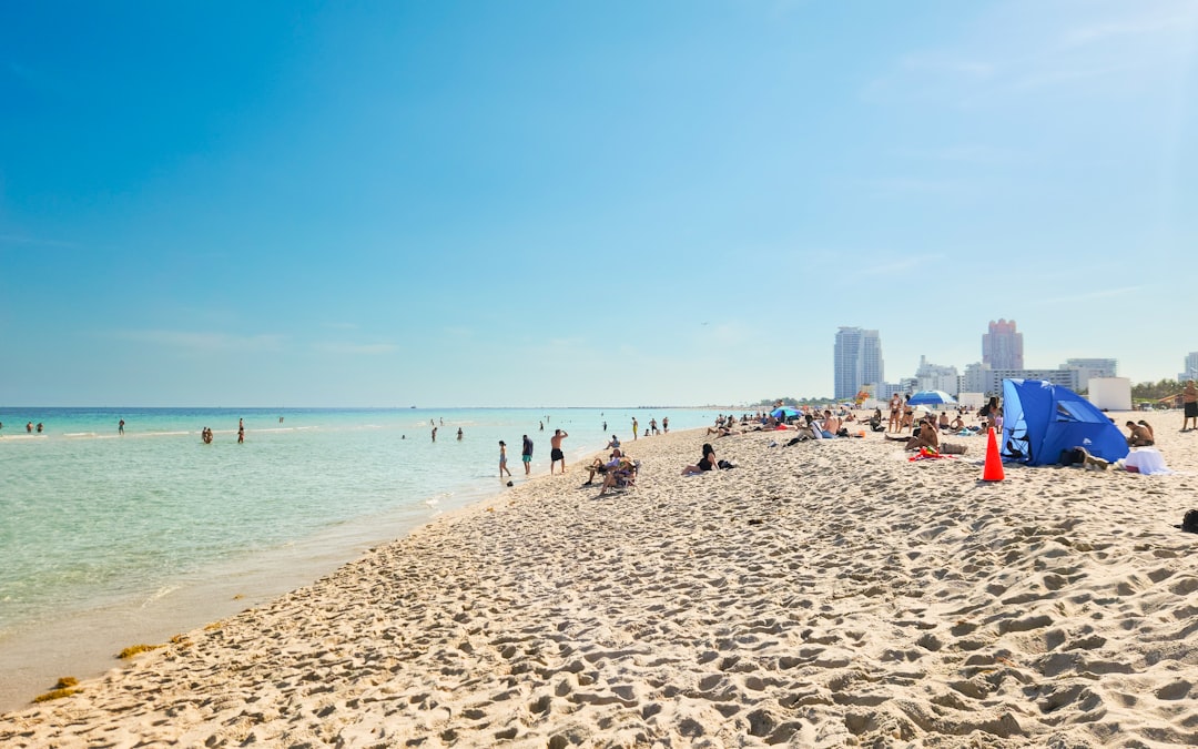A beach filled with lots of people under a blue sky